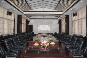 Une salle de conférence équipée d’une longue table, de chaises et d’un écran de projection.