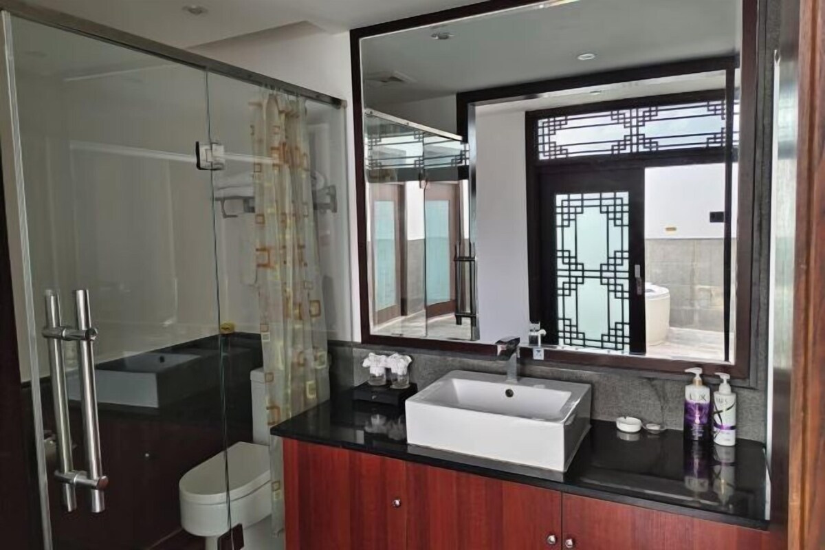Une salle de bain moderne avec une douche à parois de verre, un lavabo blanc et un grand miroir.