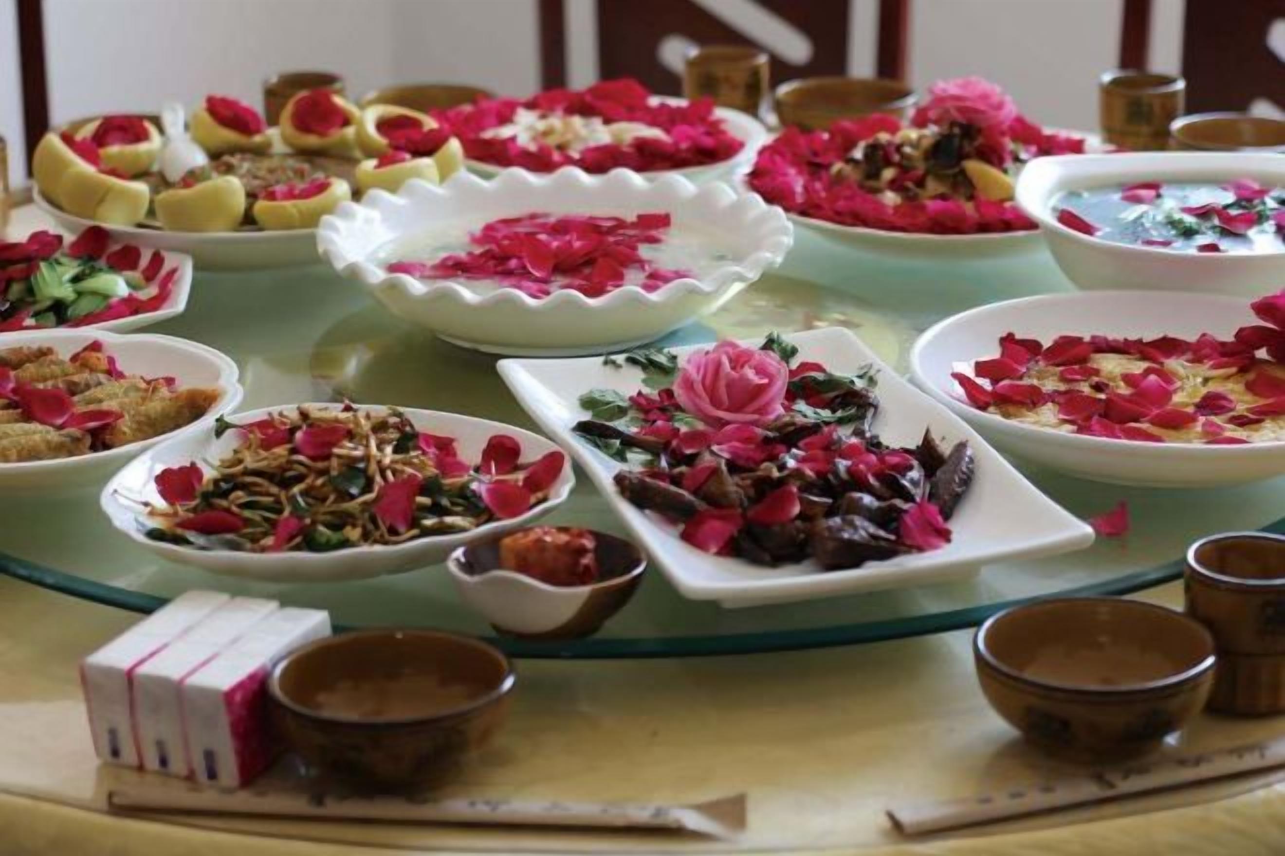 Une table sur laquelle on trouve divers plats et bols, dont certains sont décorés de pétales de fleurs roses.