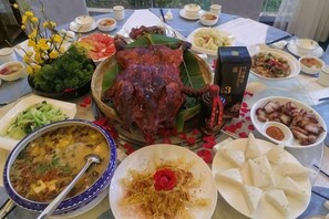 Una mesa con diversos platos, incluyendo un cerdo asado entero, tazones de sopa y platos de fideos.