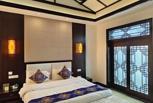 Quarto moderno com cama grande, painéis de madeira escura e janela decorativa com padrões geométricos.