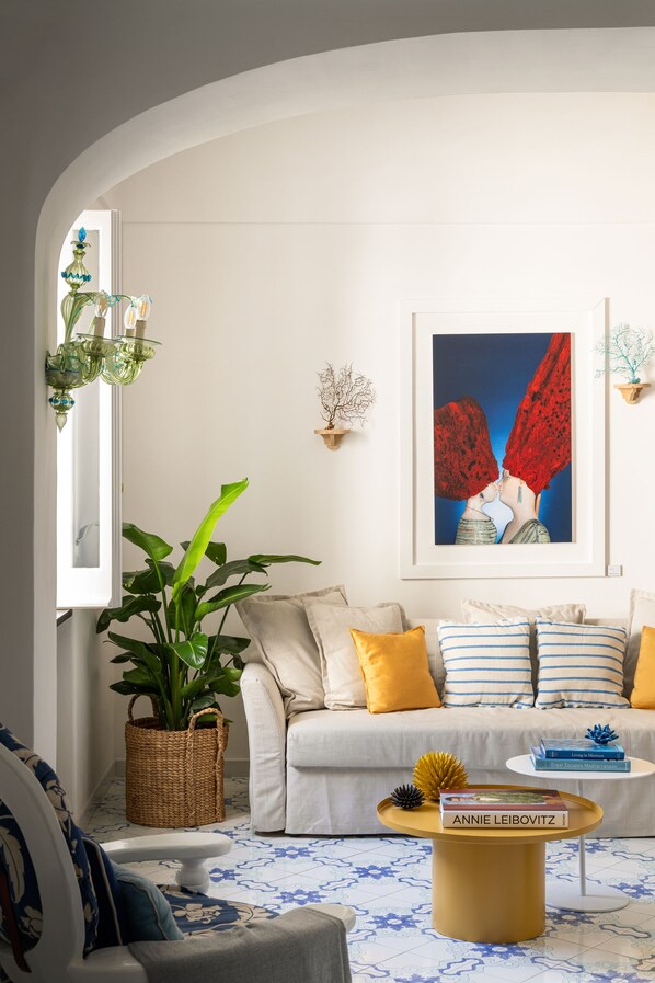 Un salon avec un canapé, une table basse, une plante en pot et une œuvre d’art encadrée accrochée au mur.