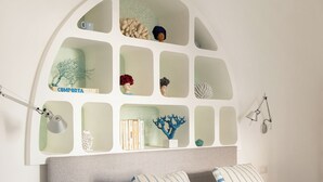 A bedroom with a bed, a bedside table, a lamp, and a wall-mounted shelf with decorative items. - Villa Michela, 2BR, 2BT, amazing patio, newly renovated (Capri)