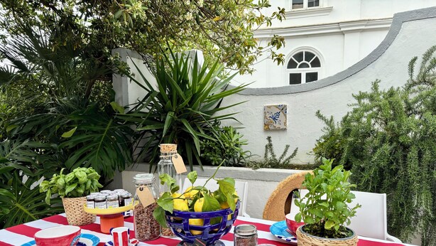 An outdoor dining area with a table set for a meal, surrounded by greenery and a building in the background. - Villa Michela, 2BR, 2BT, amazing patio, newly renovated (Capri)