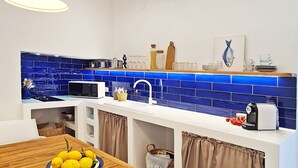 A modern kitchen with blue tiles, white countertops, and pendant lighting. - Villa Michela, 2BR, 2BT, amazing patio, newly renovated (Capri)