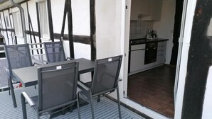 A dining area with a table and chairs, a kitchen visible through an open door, and a balcony with a railing. - Apartment Oels Witzenhausen OG incl. balcony (Witzenhausen)