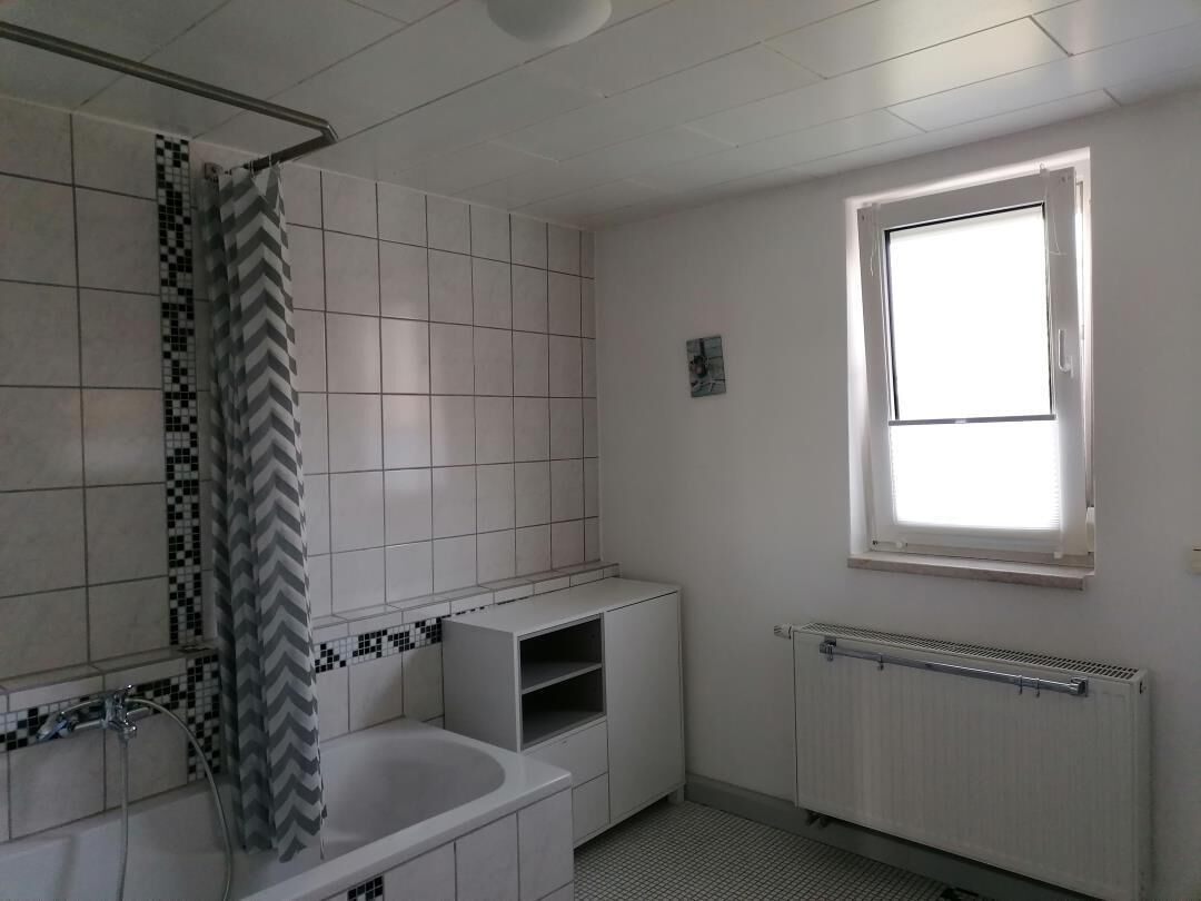 A bathroom with a shower, a bathtub, a toilet, and a window.