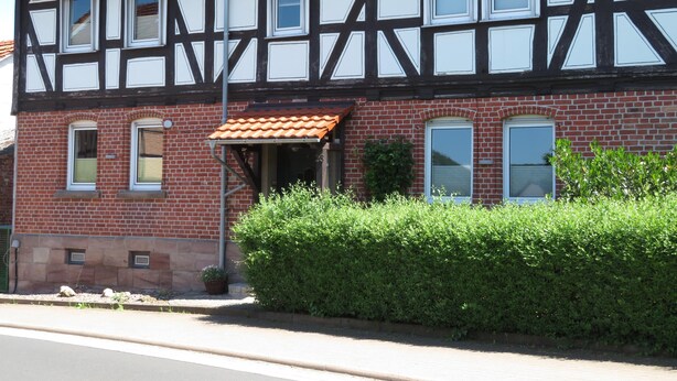 A traditional half-timbered building with a red-tiled roof, multiple windows, and a small entrance with a tiled awning. - Apartment Oels Witzenhausen OG incl. balcony (Witzenhausen)