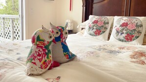 Une chambre à coucher avec une tête de lit en bois, une literie à motifs floraux et des coussins décoratifs.