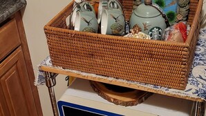Un coin cuisine comprenant un four à micro-ondes, un panier en osier contenant des ustensiles de cuisine et une assiette décorative.