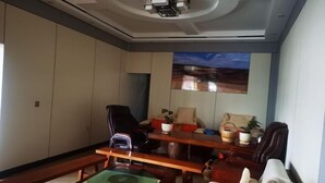 Un salon moderne comprenant un canapé, une table basse, un téléviseur fixé au mur et un projecteur au plafond.