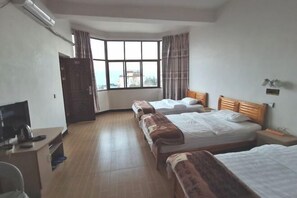 A hotel room with two beds, a desk with a chair, a TV, and a window with curtains. - Hongtu Qicai Renjia Hostel (Kunming)