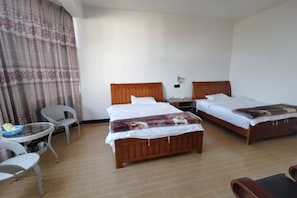 A hotel room with two single beds, a small table with chairs, and a large window with curtains. - Hongtu Qicai Renjia Hostel (Kunming)