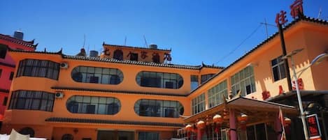 A multi-story building with a traditional architectural style, featuring a ground-level commercial area with a storefront and a parking lot.