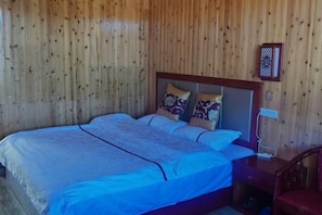 A double bed with a wooden headboard, two pillows, and a bedside table with a lamp. - Hongtu Qicai Renjia Hostel (Kunming)