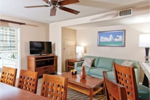 Relax in this stylish living room with a flat-screen TV, comfortable sofa, and ceiling fan.