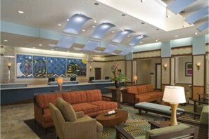 Welcome to our lobby, featuring a seating area with sofas and armchairs, a reception desk, and a striking abstract painting.