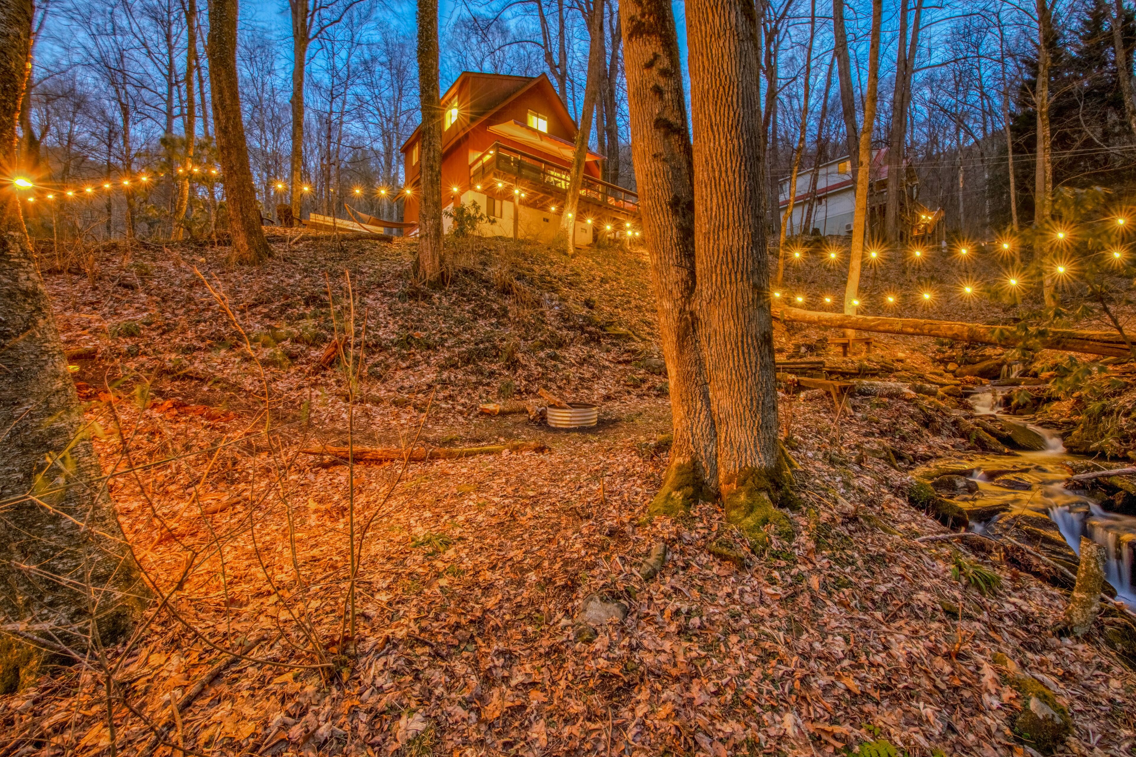 Hillside home by a stream with hot tub, firepit, deck, & seasonal mountain views