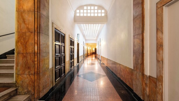 A long, narrow hallway with marble walls and a polished floor, leading to a staircase and a door at the end. - Royal Rooms Corso (Rome)