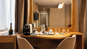 A hotel room with a wooden desk, a coffee maker, a kettle, and a mirror reflecting the room. - Royal Rooms Corso (Rome)