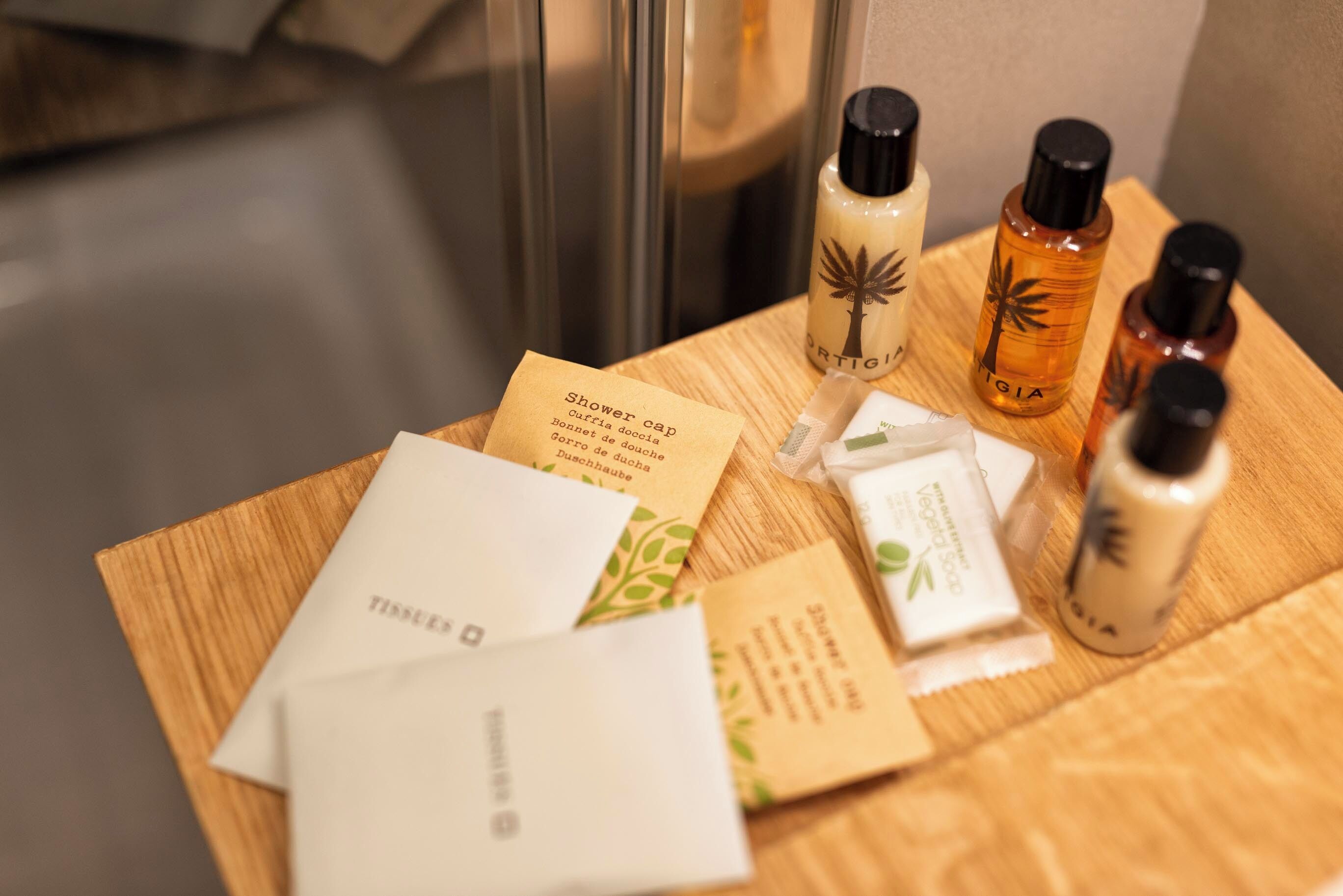 Des articles de toilette et une serviette sur une surface en bois, dans une chambre d’hôtel.