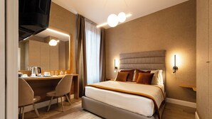 A hotel room with a large bed, a desk with a chair, a mirror, and a television. - Royal Rooms Corso (Rome)