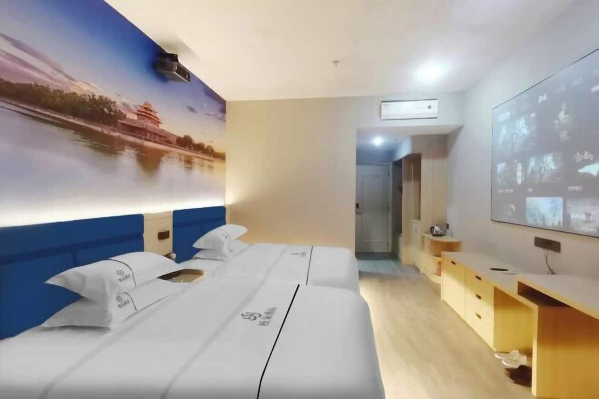 Una habitación de hotel con una cama grande, un escritorio y una pantalla de televisión mostrando imágenes.