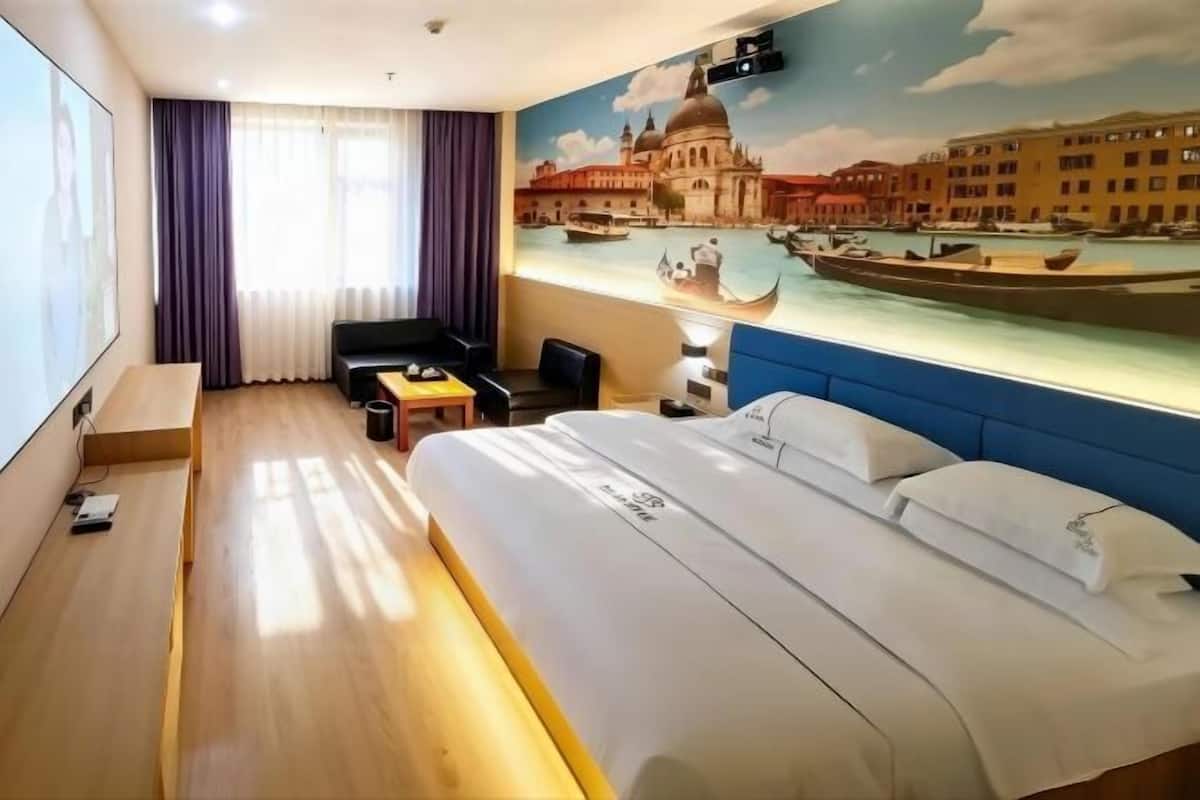 Habitación de hotel con cama, escritorio, silla, televisor y un mural de Venecia.