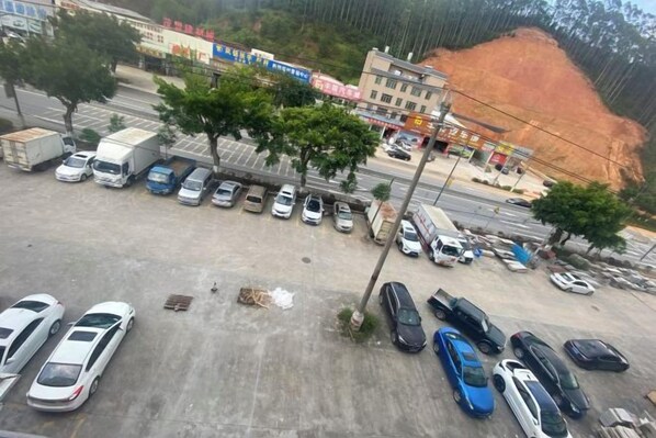 A parking lot with various vehicles, including cars and trucks, and a dirt hill in the background. - Yaduo Hotel (Xinfeng County Yunjishan Scenic Area) (Xinfeng)