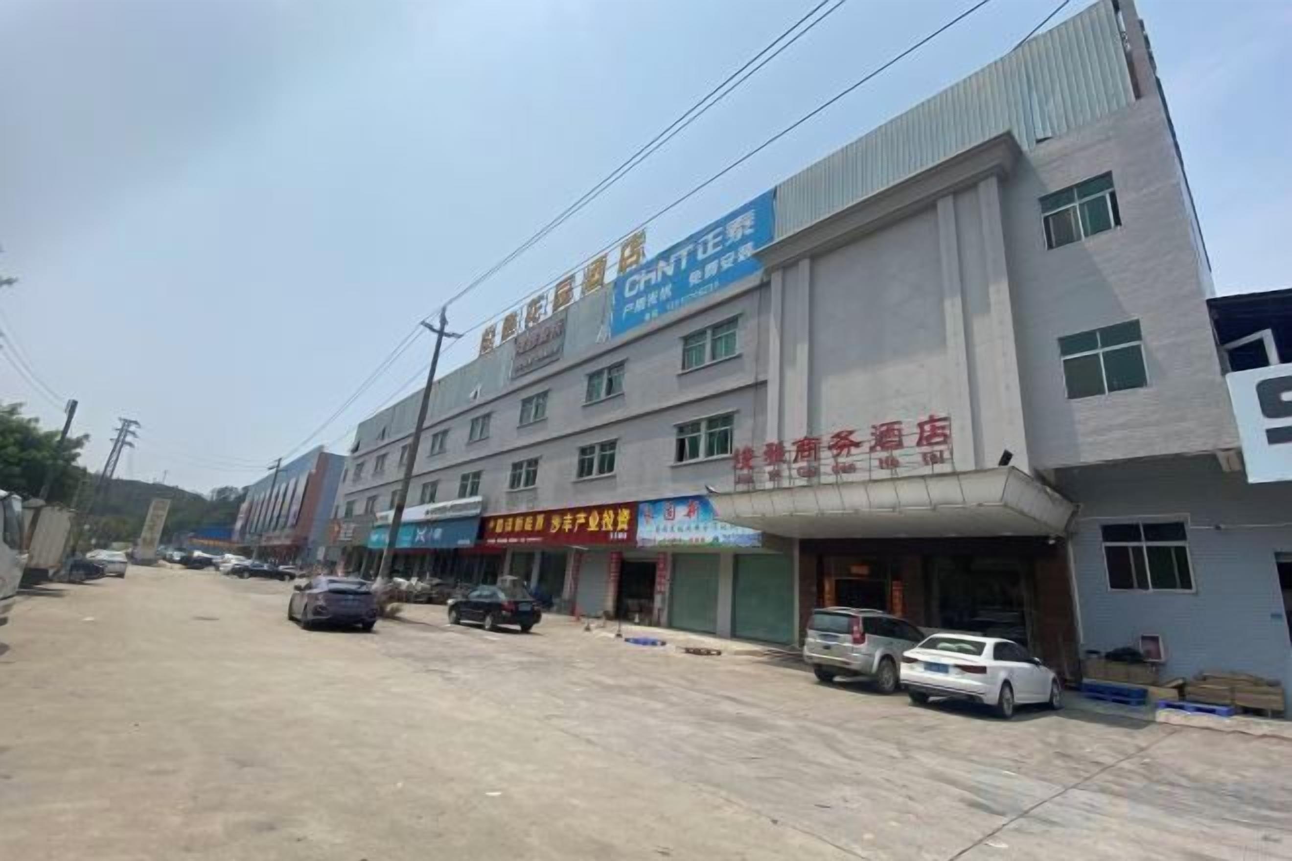 A multi-story building with commercial signage, a parking area, and a street view.