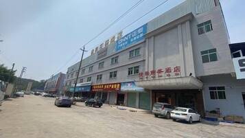 A multi-story building with commercial signage, a parking area, and a street view.