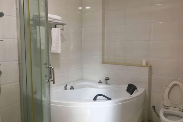 A bathroom with a glass-enclosed shower, a white bathtub, and a toilet. - Yaduo Hotel (Xinfeng County Yunjishan Scenic Area) (Xinfeng)
