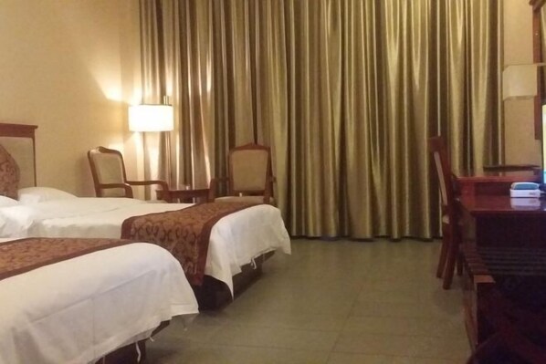Una habitación de hotel con dos camas, un escritorio, una silla y una lámpara.