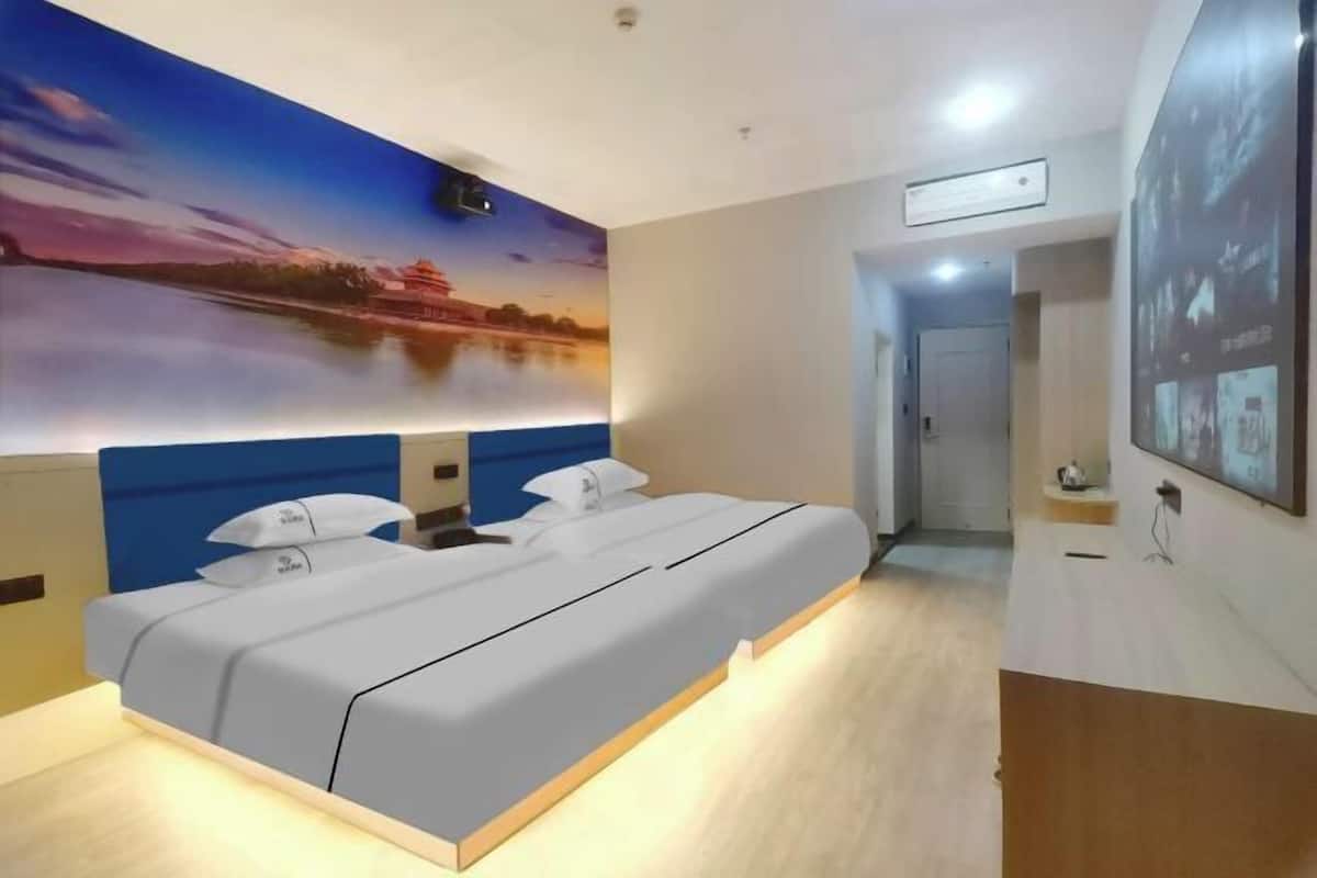 Una habitación de hotel moderna con una cama grande, un cuadro de un atardecer sobre el agua y un pasillo que conduce a un baño.