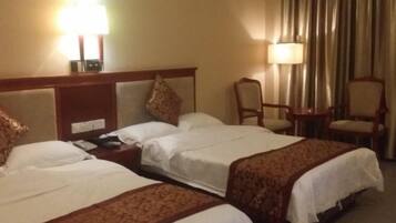 Habitación de hotel con dos camas, una mesita de noche, una silla y una lámpara.