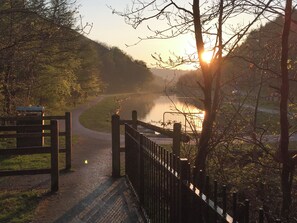 A pathway leading to a body of water with a metal gate and a fence on the right. - 3 bedroom accommodation in Crosskeys, near Newport (Crosskeys, near Newport)