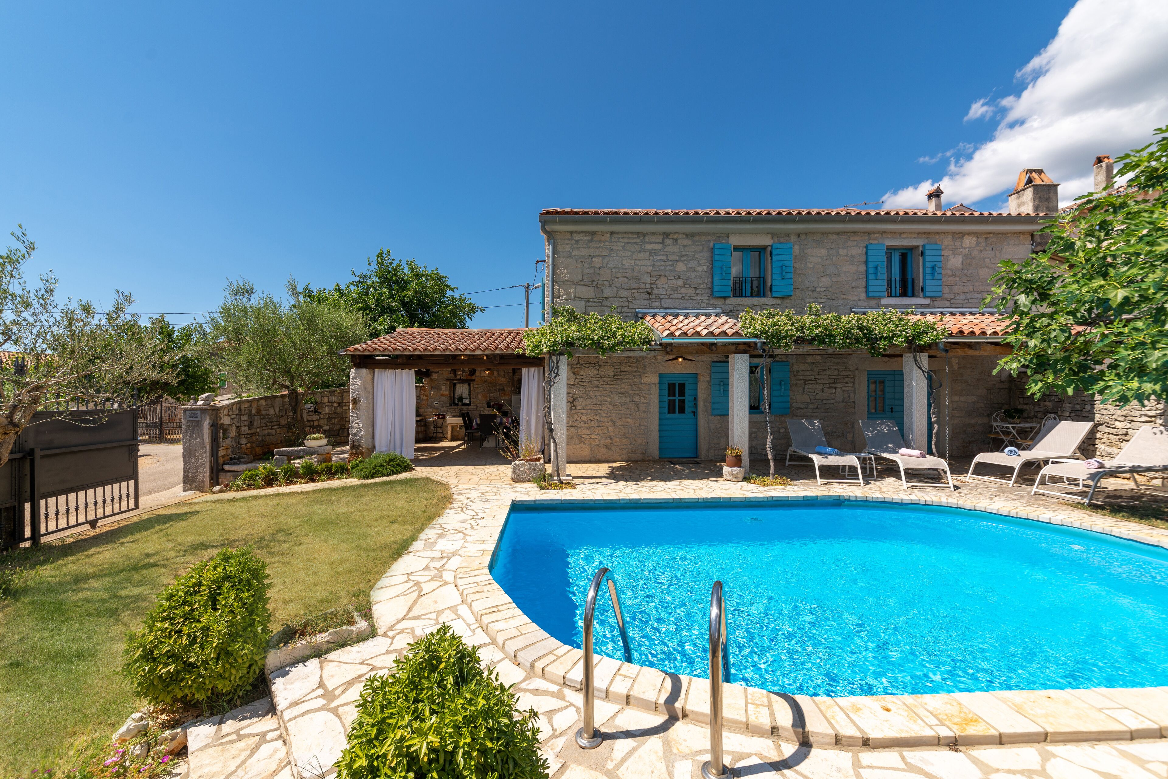 A stone house with a swimming pool, outdoor seating, and a well-maintained garden.
