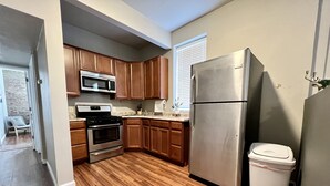 Una cocina con armarios de madera, electrodomésticos de acero inoxidable y un bote de basura.