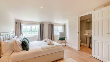 A spacious bedroom with a large bed, a chair, and a view of the outdoors through the window.