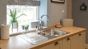 A kitchen with a sink, a window with a plant, and a framed picture on the wall. - 1 bedroom accommodation in Alnwick (Alnwick)