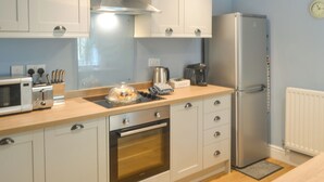 A modern kitchen with white cabinets, a stainless steel range hood, a built-in oven, a microwave, a refrigerator, and a coffee maker. - 1 bedroom accommodation in Alnwick (Alnwick)