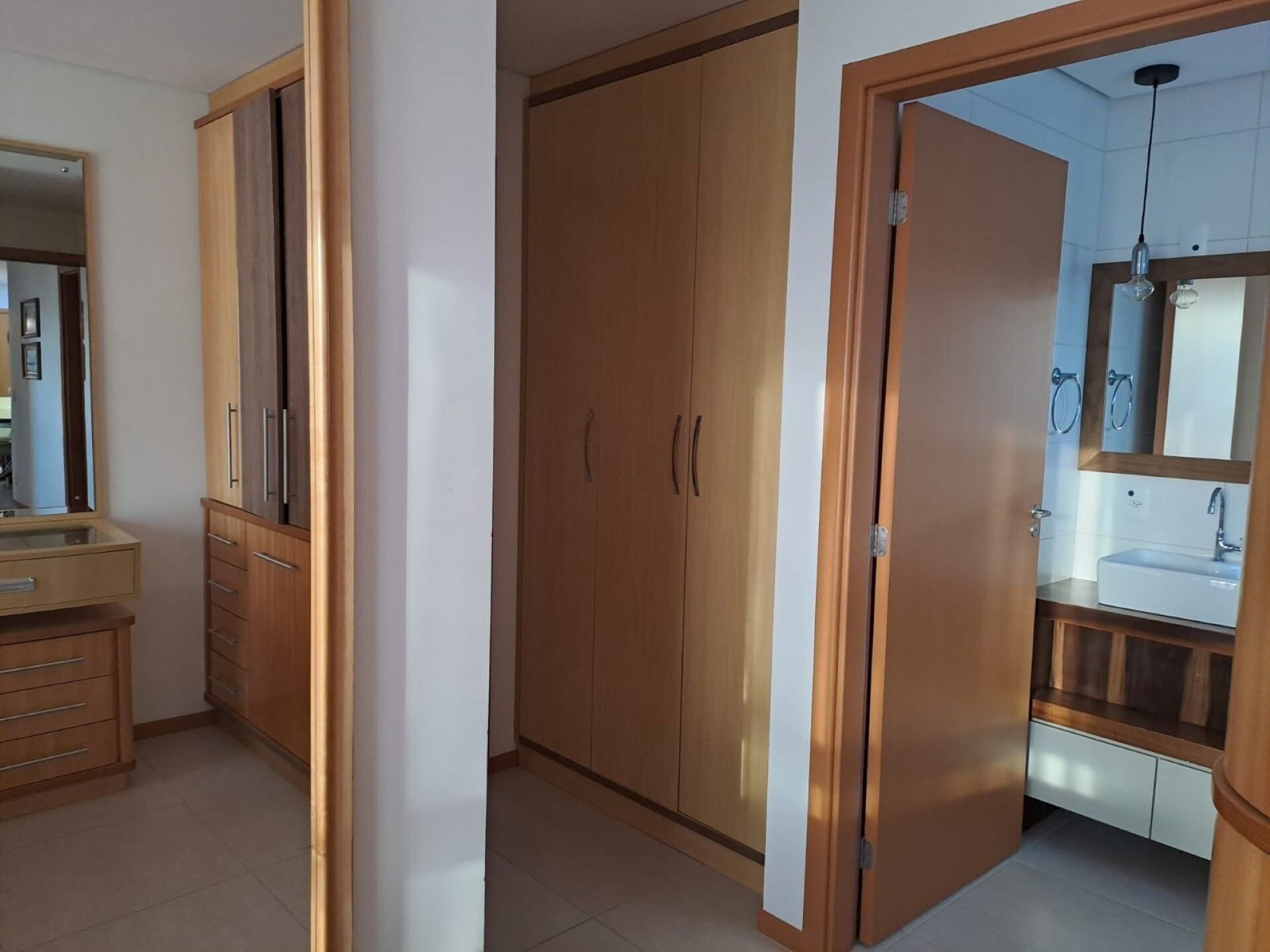 Ein Zimmer mit Holzschrank, Spiegel und einem Badezimmer mit Waschbecken und Spiegel.