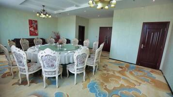 A dining area with a round table surrounded by chairs, a patterned carpet, and a chandelier.