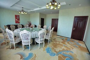 Un comedor con una mesa redonda rodeada de sillas, una alfombra estampada y un candelabro.