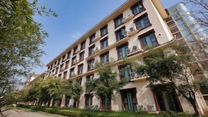 Un edificio de varios pisos con fachada color beige, múltiples ventanas y unidades de aire acondicionado.