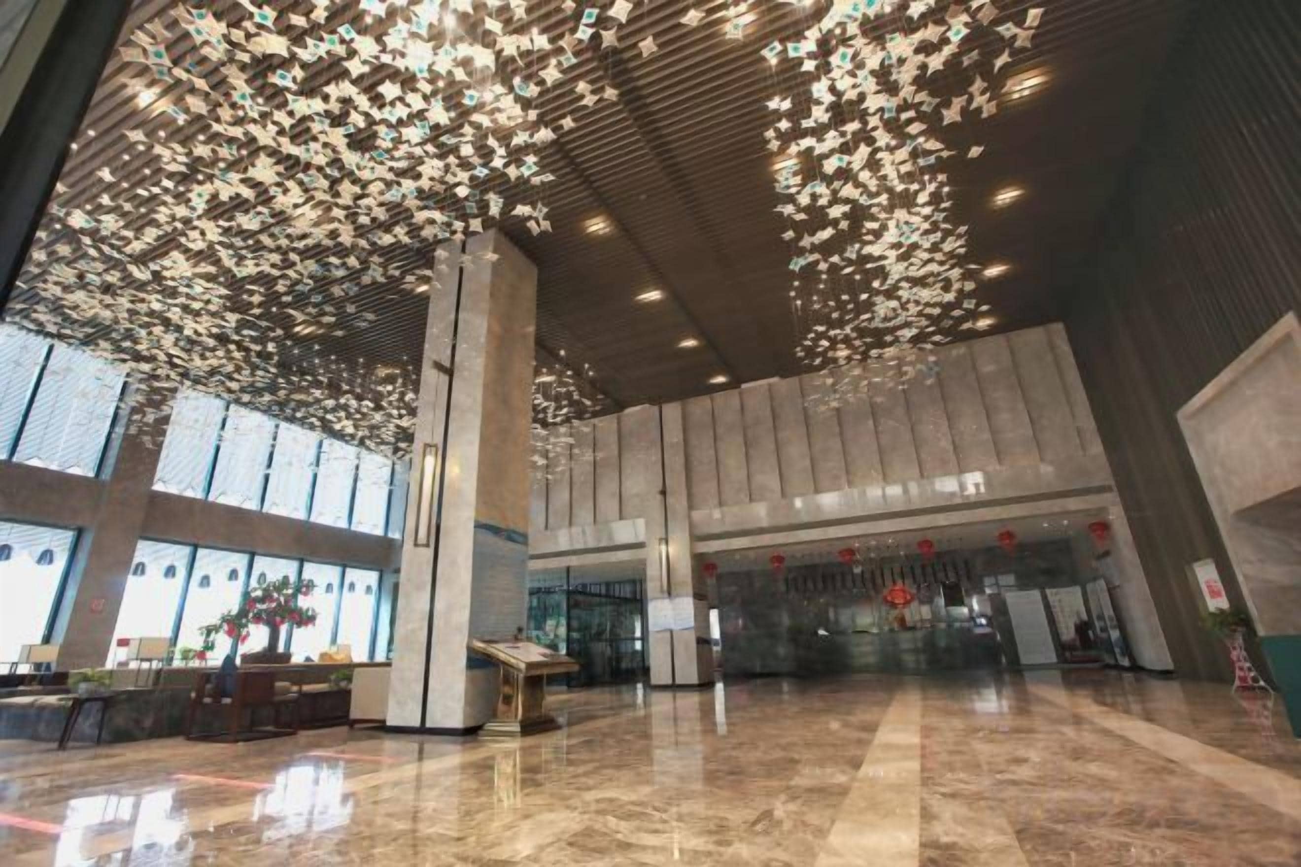 A spacious lobby with a high ceiling, large windows, and a reflective floor.
