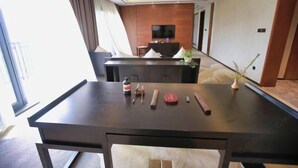 Una habitación de hotel moderna con un escritorio de madera oscura, un televisor de pantalla plana y un amplio ventanal con cortinas.