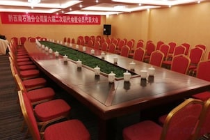 A conference room with a long table, red chairs, and a carpeted floor.