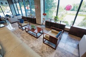 Un amplio vestíbulo con zonas de estar, una mesa de centro y grandes ventanales con vistas al exterior.