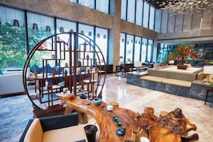 Un vestíbulo amplio con una zona de estar central, una gran mesa de centro de madera y una escultura decorativa de metal.